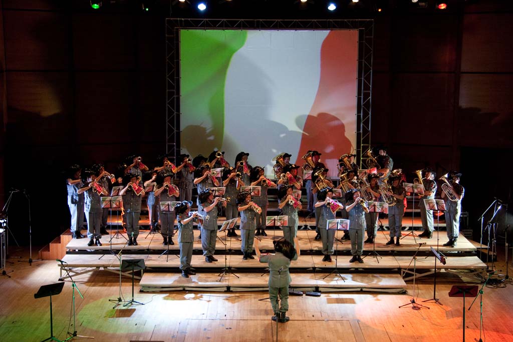 L'immagine del tricolore fa da sfondo all'esibizione  della Fanfara dei Bersaglieri.
